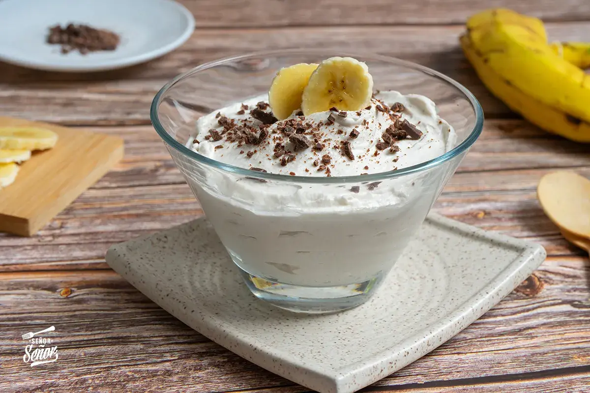 Delicioso mousse de plátano cremoso, adornado con trozos de chocolate y rodajas de plátano fresco.