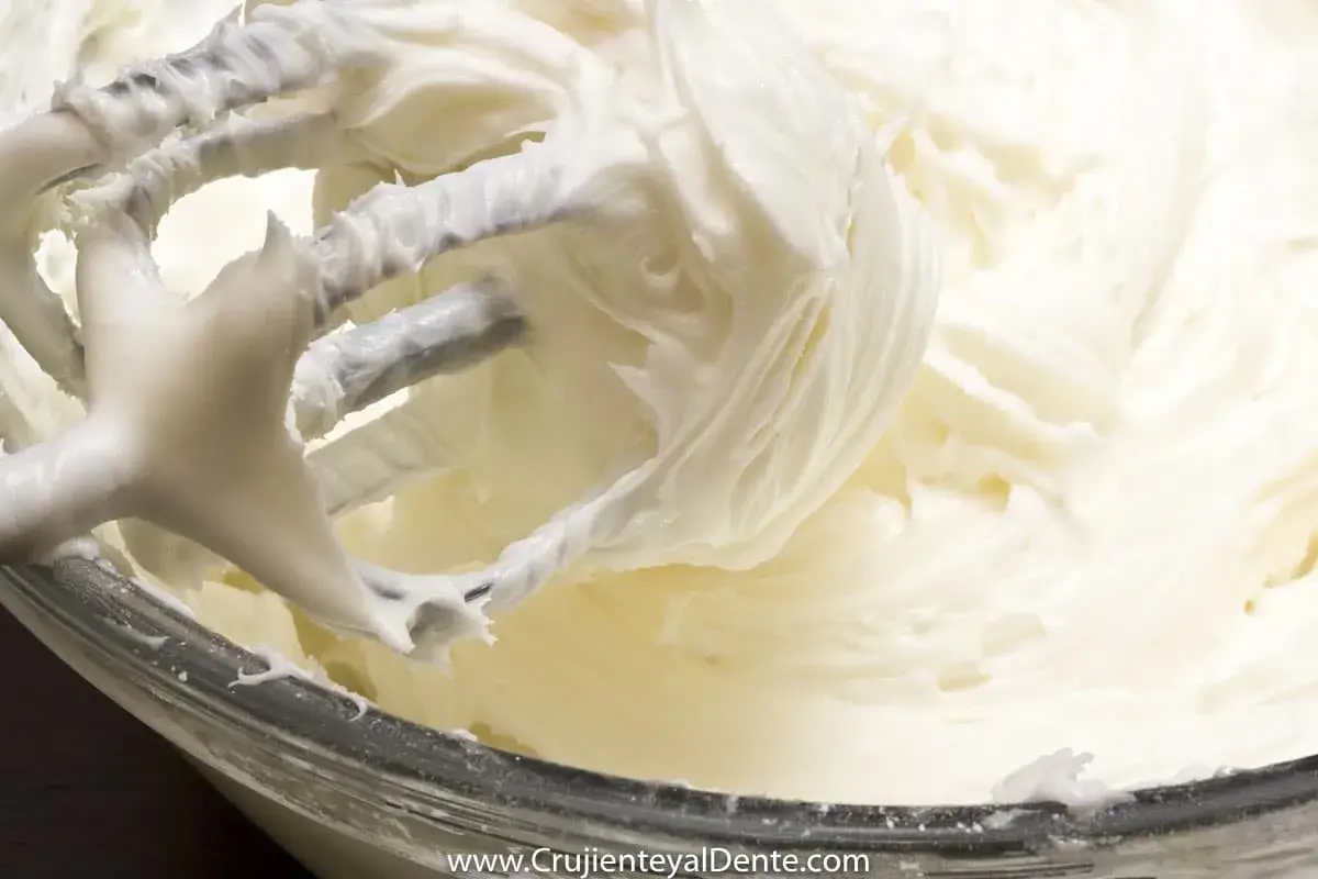 Batidora mezclando un cremoso frosting de queso, listo para decorar.