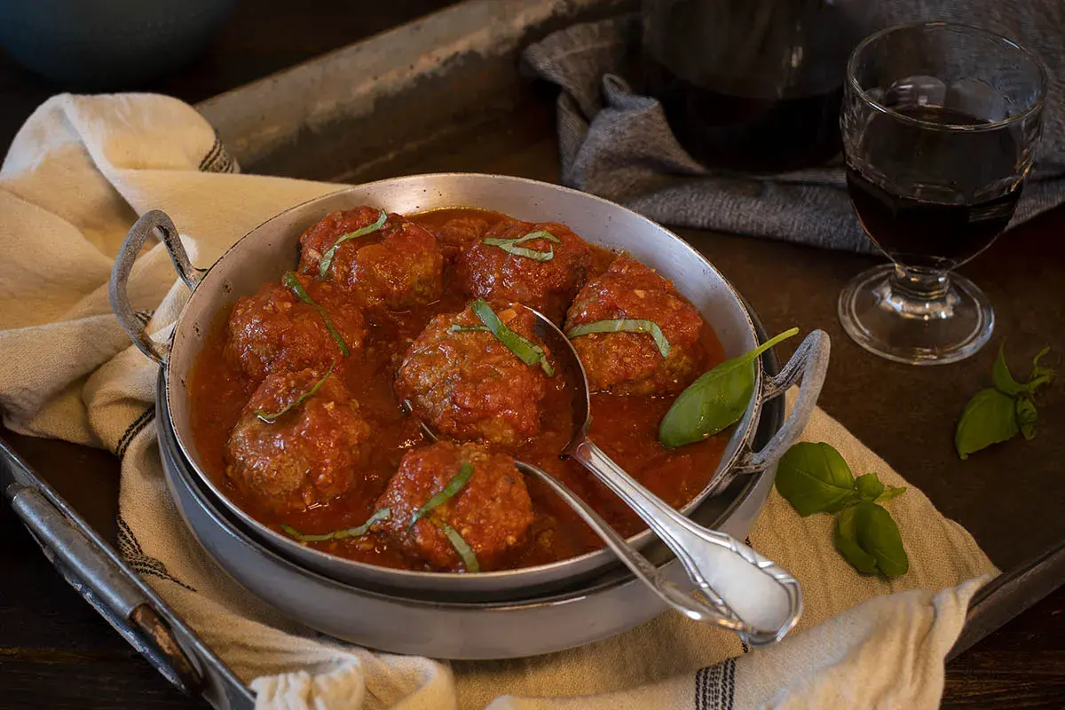 Sabrosas polpette al sugo, jugosas albóndigas en salsa de tomate, adornadas con albahaca fresca.