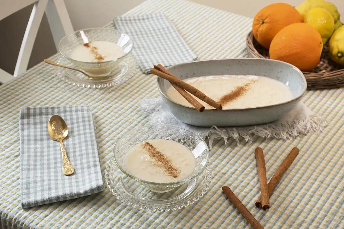 Delicioso arroz con leche sin azúcar, servido en cuencos de cristal y un plato grande, decorado con canela y acompañado de naranjas y limones.