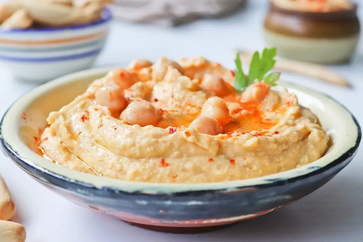 Cremoso hummus de garbanzos, decorado con garbanzos enteros, pimentón y perejil. Perfecto para dipear.