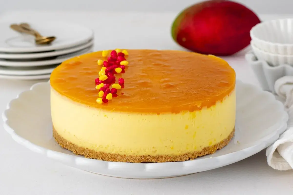 Deliciosa tarta de mango con una capa superior de gelatina brillante y decorada con grageas rojas y amarillas.
