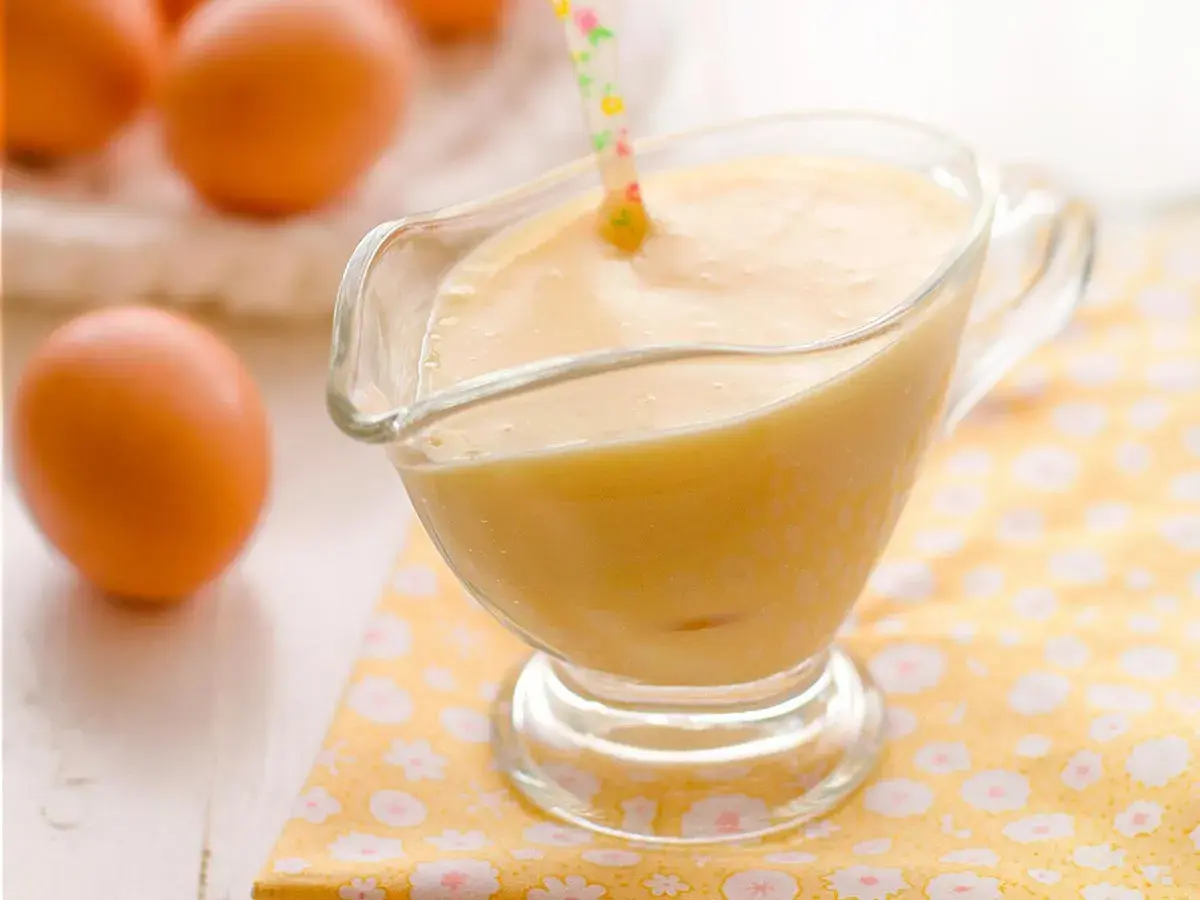 Crema pastelera perfecta hecha en Thermomix, lista para usar. Huevos frescos en el fondo.