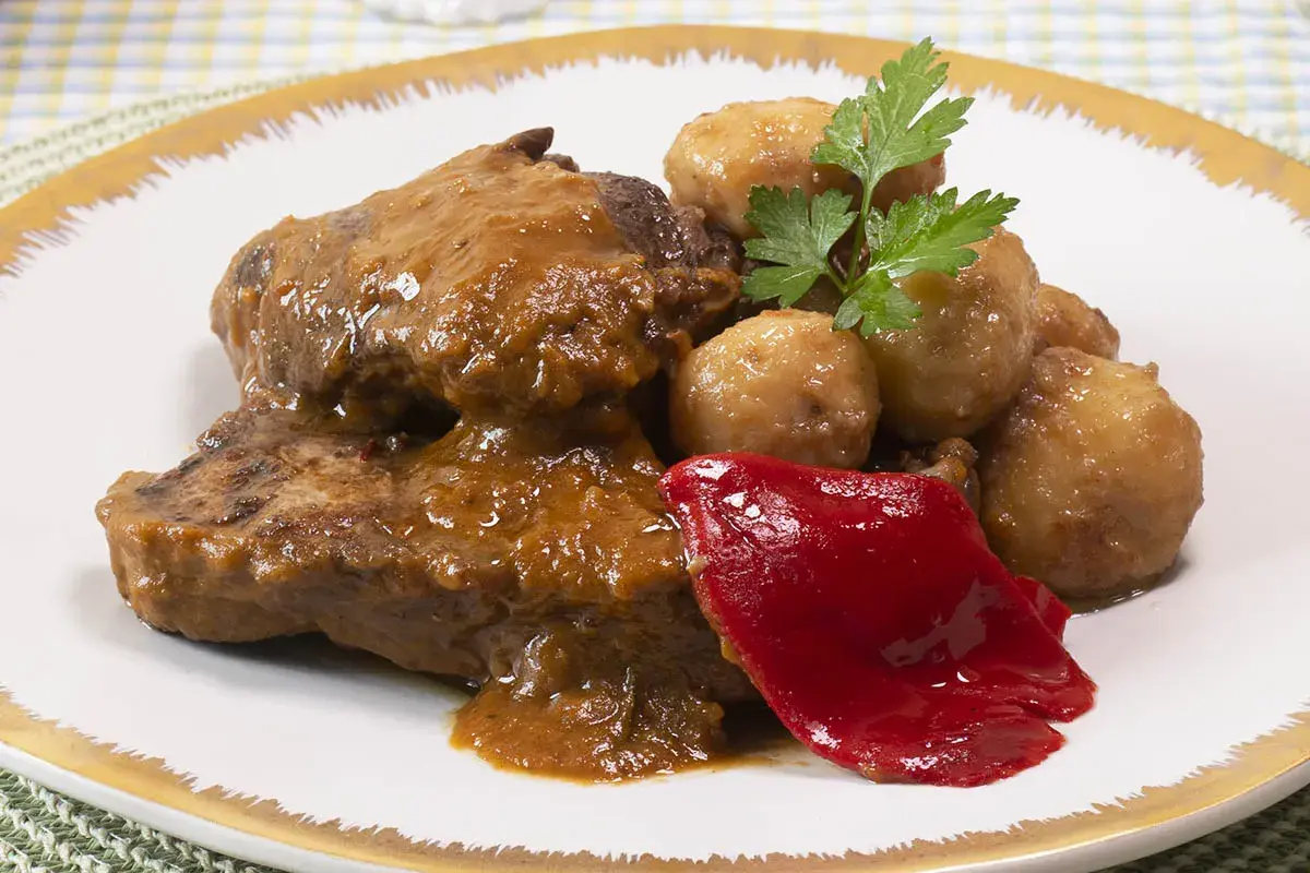 Tierna ternera guisada con patatas, acompañada de pimiento rojo y perejil. Un plato casero y delicioso.