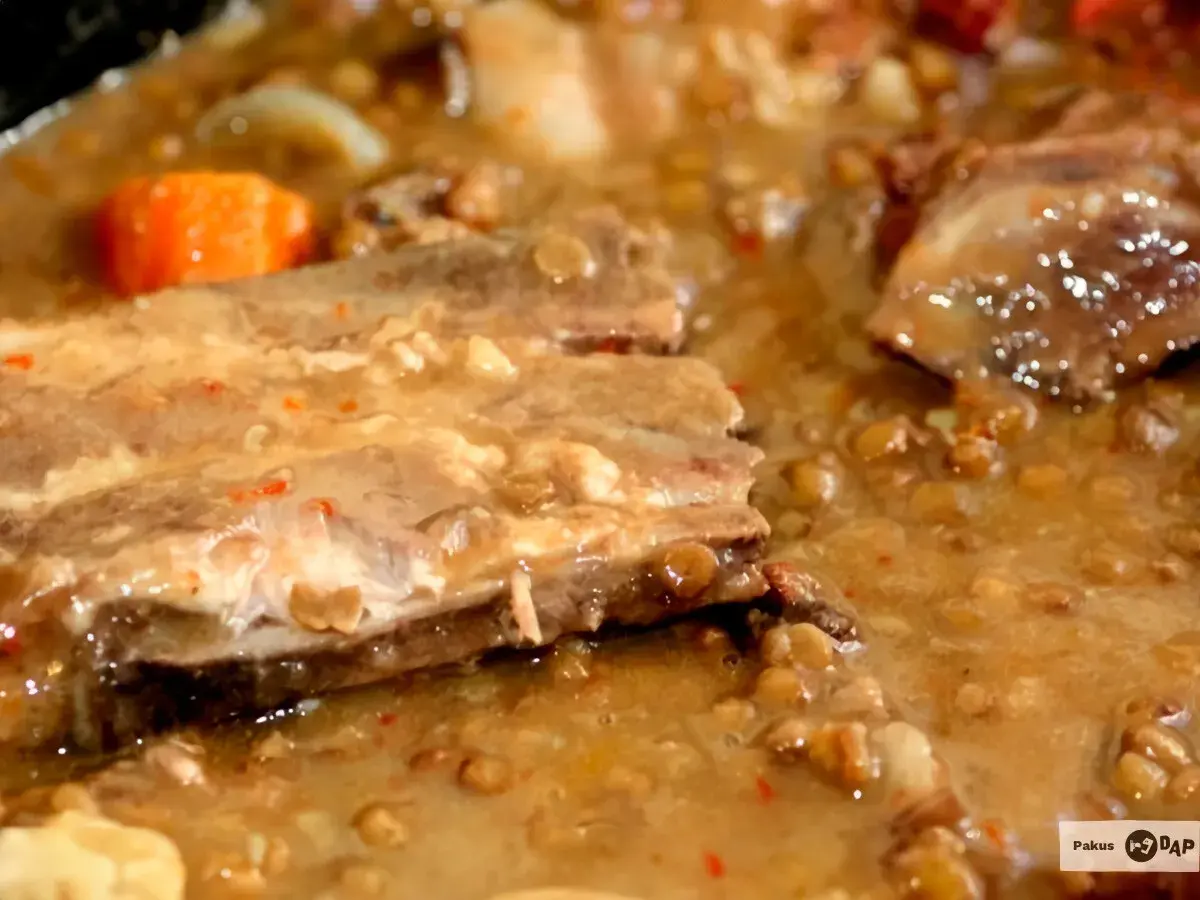 Un plato humeante de lentejas con costillas, con trozos de zanahoria y un caldo espeso y sabroso.