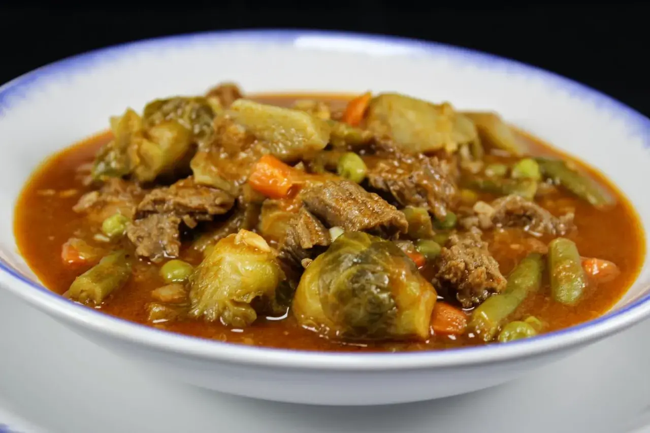 Un reconfortante plato de menestra de verduras con carne de la abuela, lleno de tiernos trozos de carne, coles de Bruselas, zanahorias y judías verdes en una rica salsa.