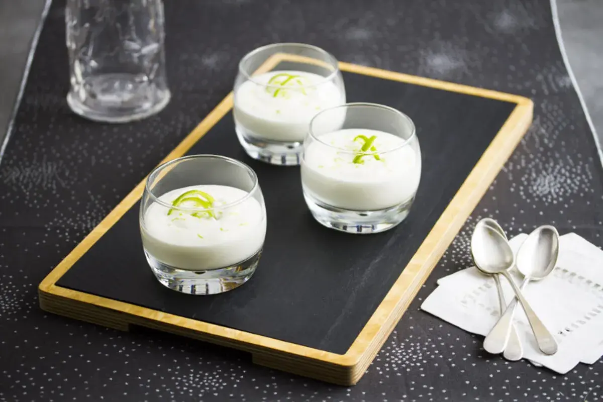 Tres vasitos de cremoso mousse de limón, decorados con ralladura verde, listos para disfrutar.