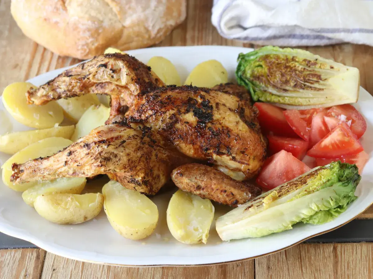 Pollo a la brasa jugoso y dorado, acompañado de papas amarillas, tomates frescos y lechuga a la parrilla. Un festín para disfrutar.