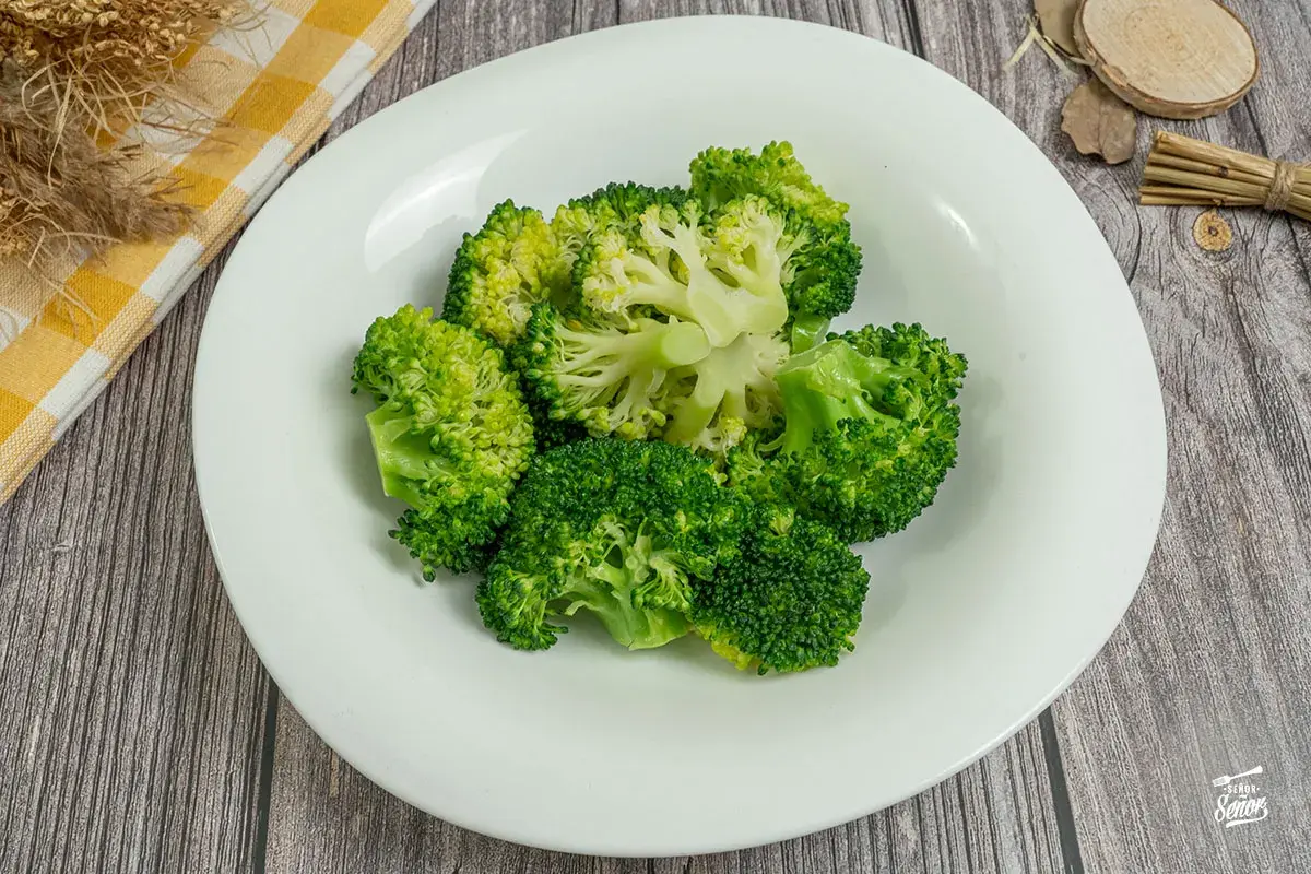 Brocoli al vapor, fresco y verde, servido en un plato blanco. Un toque saludable y delicioso.
