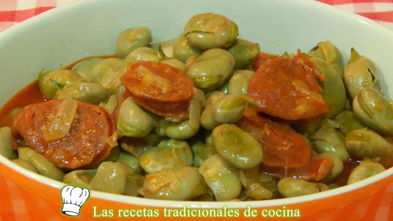 Un plato humeante de habas tiernas con rodajas de chorizo español, todo bañado en una salsa sabrosa.