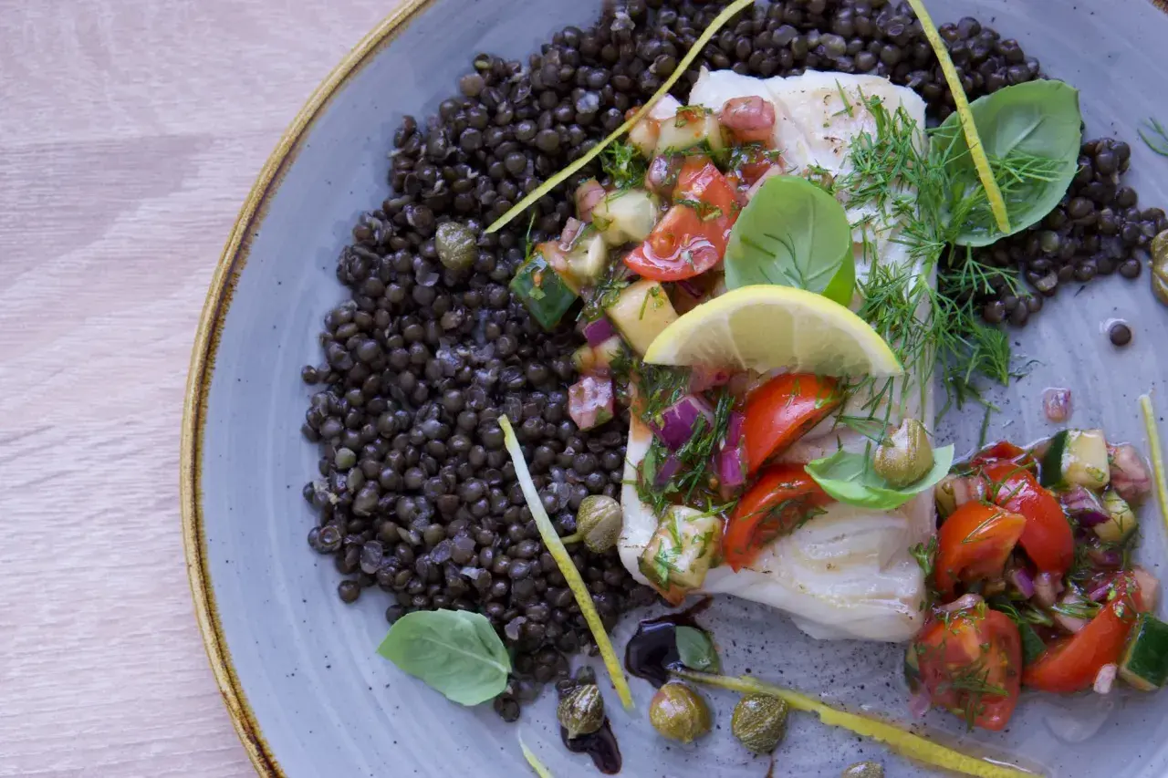 Filete de bacalao con ensalada de tomate y pepino, acompañado de lentejas. Una de las mejores recetas de bacalao.