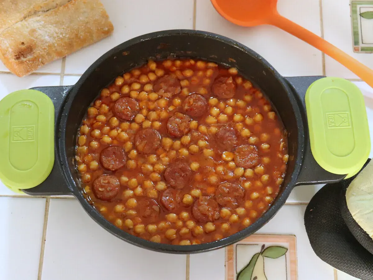 Un plato humeante de garbanzos con chorizo, listo para disfrutar con pan crujiente.
