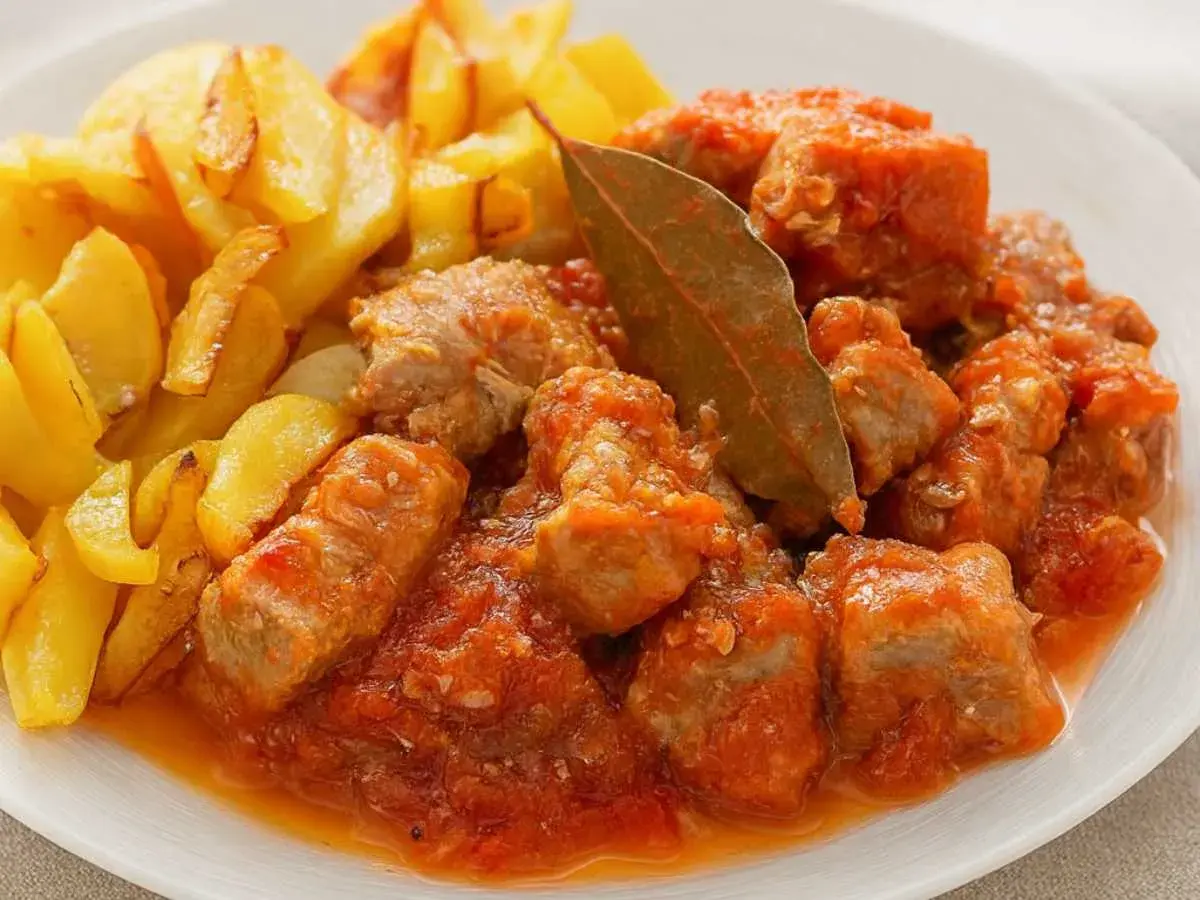 Magro con tomate, la receta de la abuela, servido con patatas fritas doradas. Un plato casero lleno de sabor.