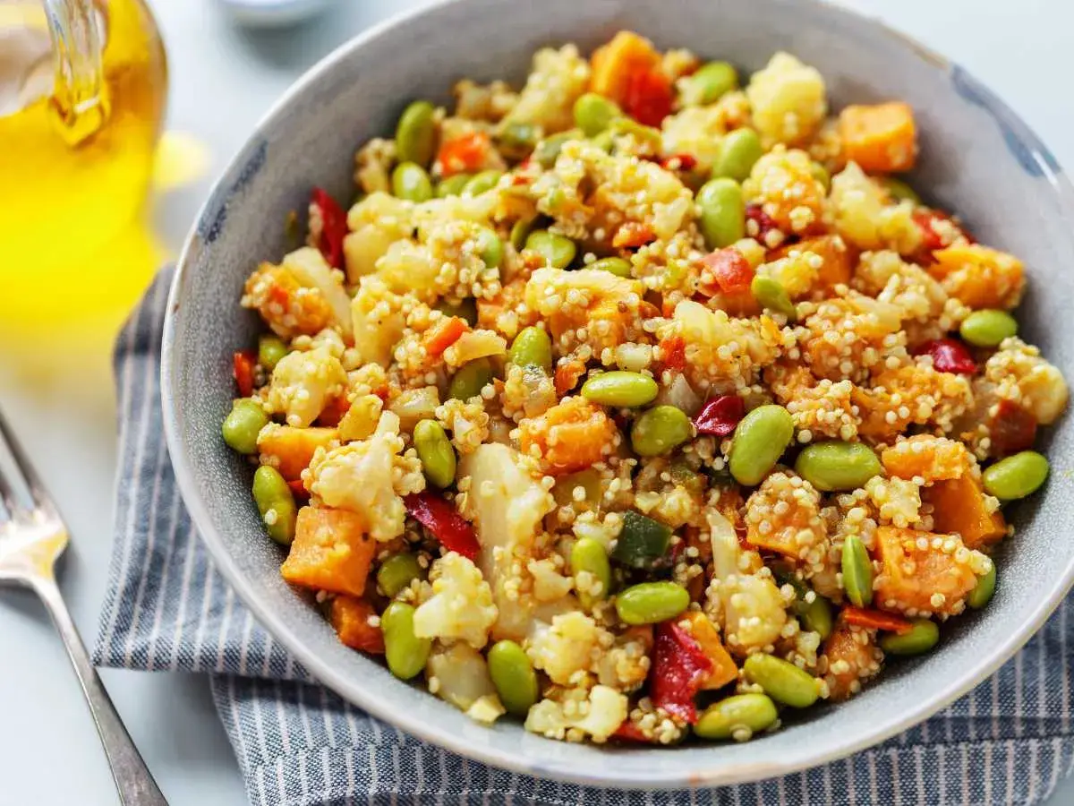Un tazón de quinoa con verduras coloridas: edamame, coliflor, zanahoria y pimiento rojo. Un plato saludable y delicioso.