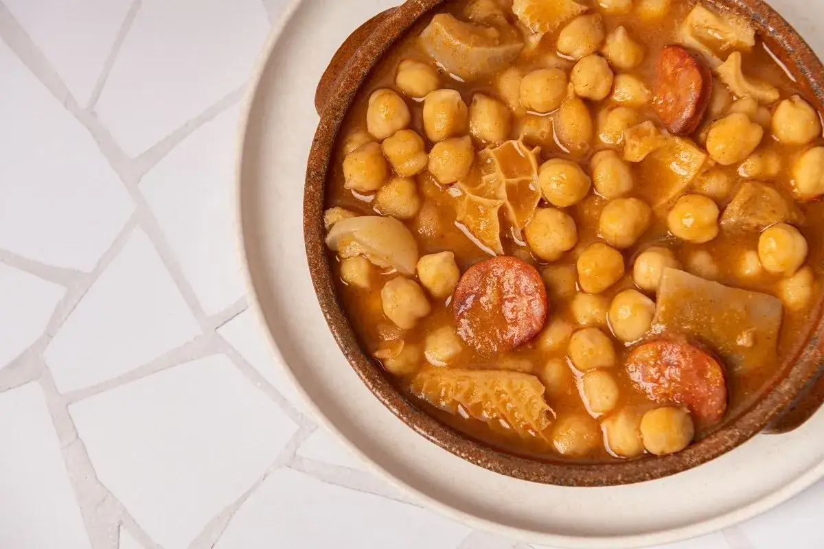 Un plato de barro con callos con garbanzos de bote, chorizo y trozos de carne. Un guiso tradicional y reconfortante.