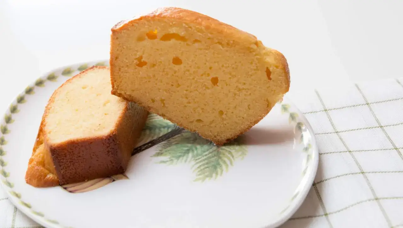 Dos rebanadas de bizcocho de leche condensada, esponjosas y doradas, servidas en un plato con dise&ntilde;o de palmeras.