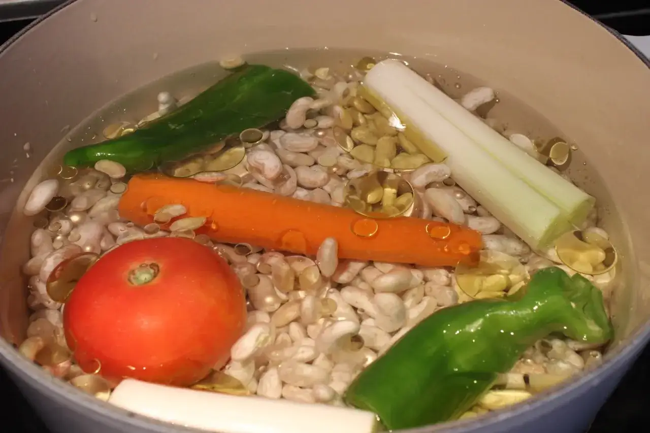 Pochas a la riojana en cocción: judías blancas, zanahoria, tomate, pimiento verde y puerro en una olla.