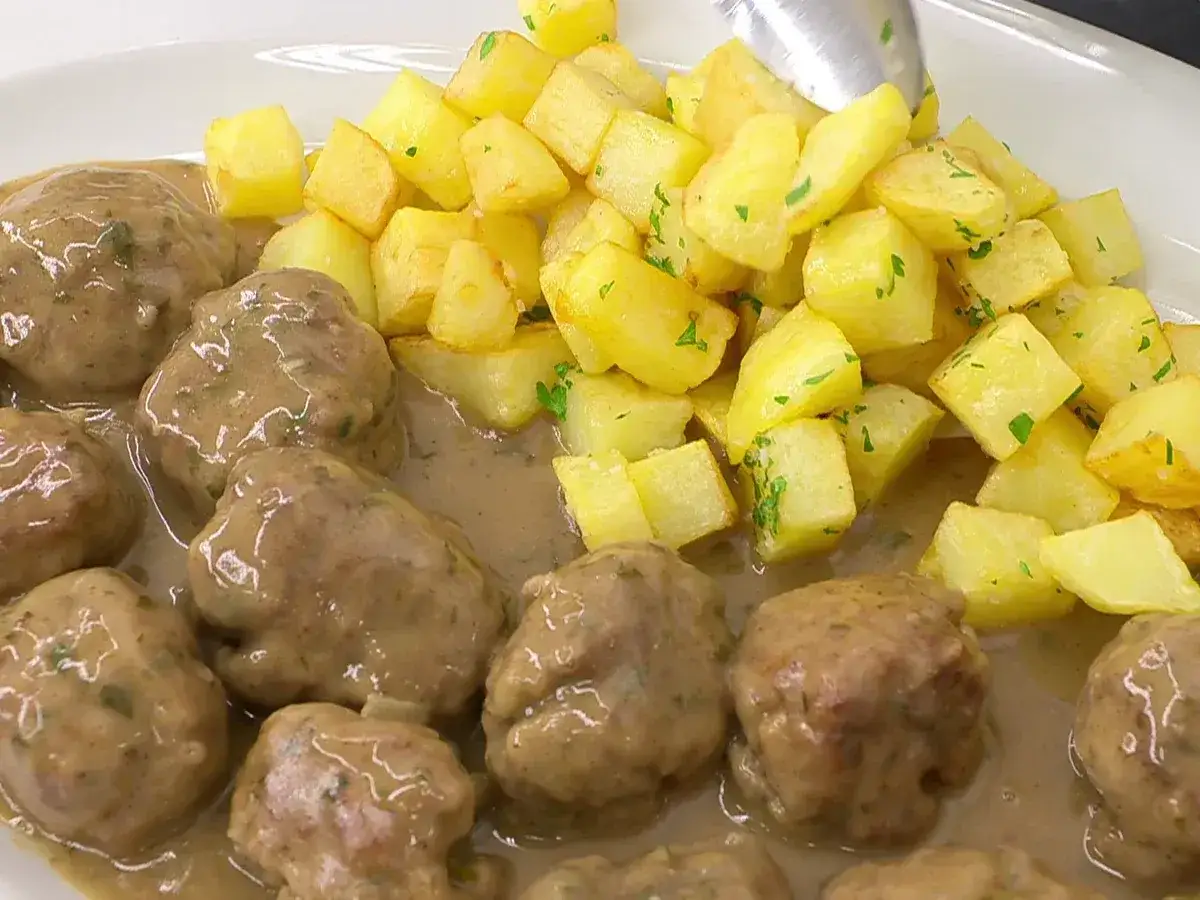 Albóndigas en salsa Arguiñano, jugosas y tiernas, acompañadas de patatas fritas doradas y perejil picado. ¡Un plato casero delicioso!
