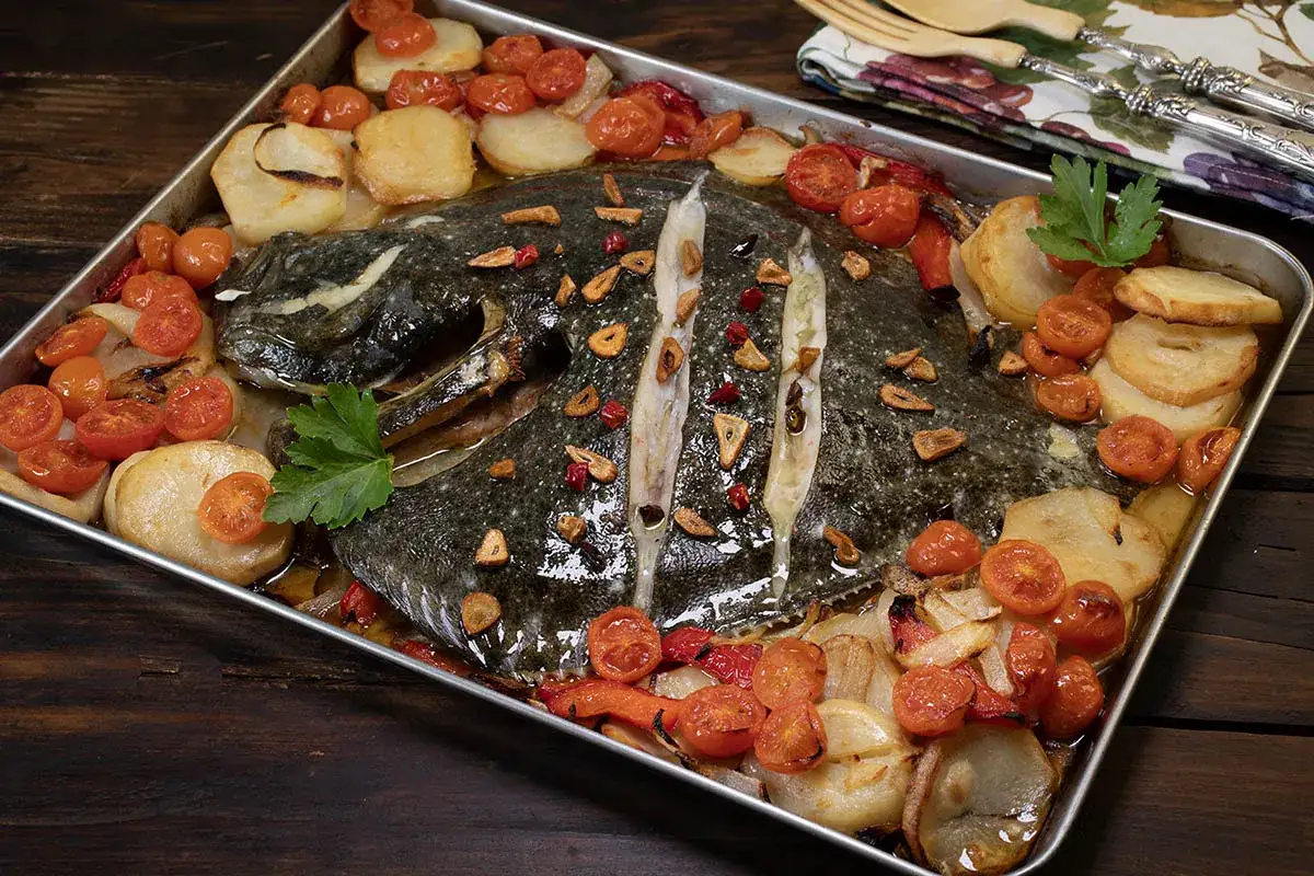 Rodaballo al horno con patatas, tomates cherry y ajo. El tiempo perfecto para un plato delicioso.