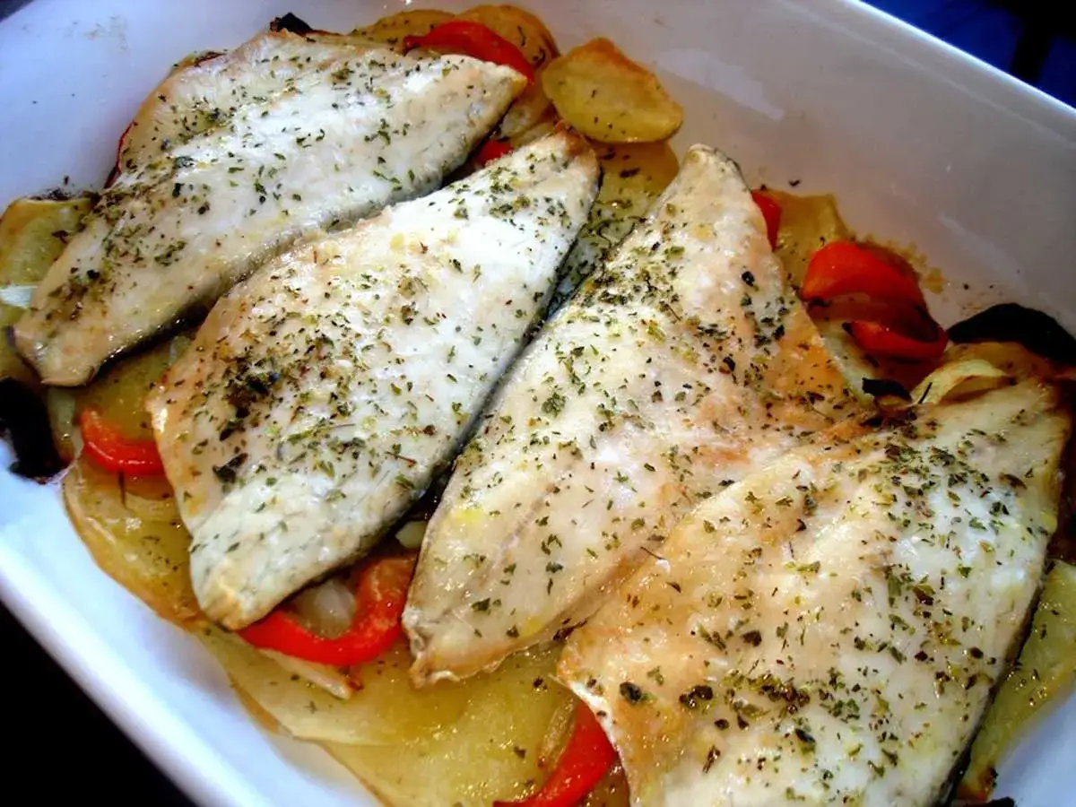 Filetes de lubina al horno, tiernos y jugosos, sobre una cama de patatas y pimientos rojos. ¡Un plato delicioso!