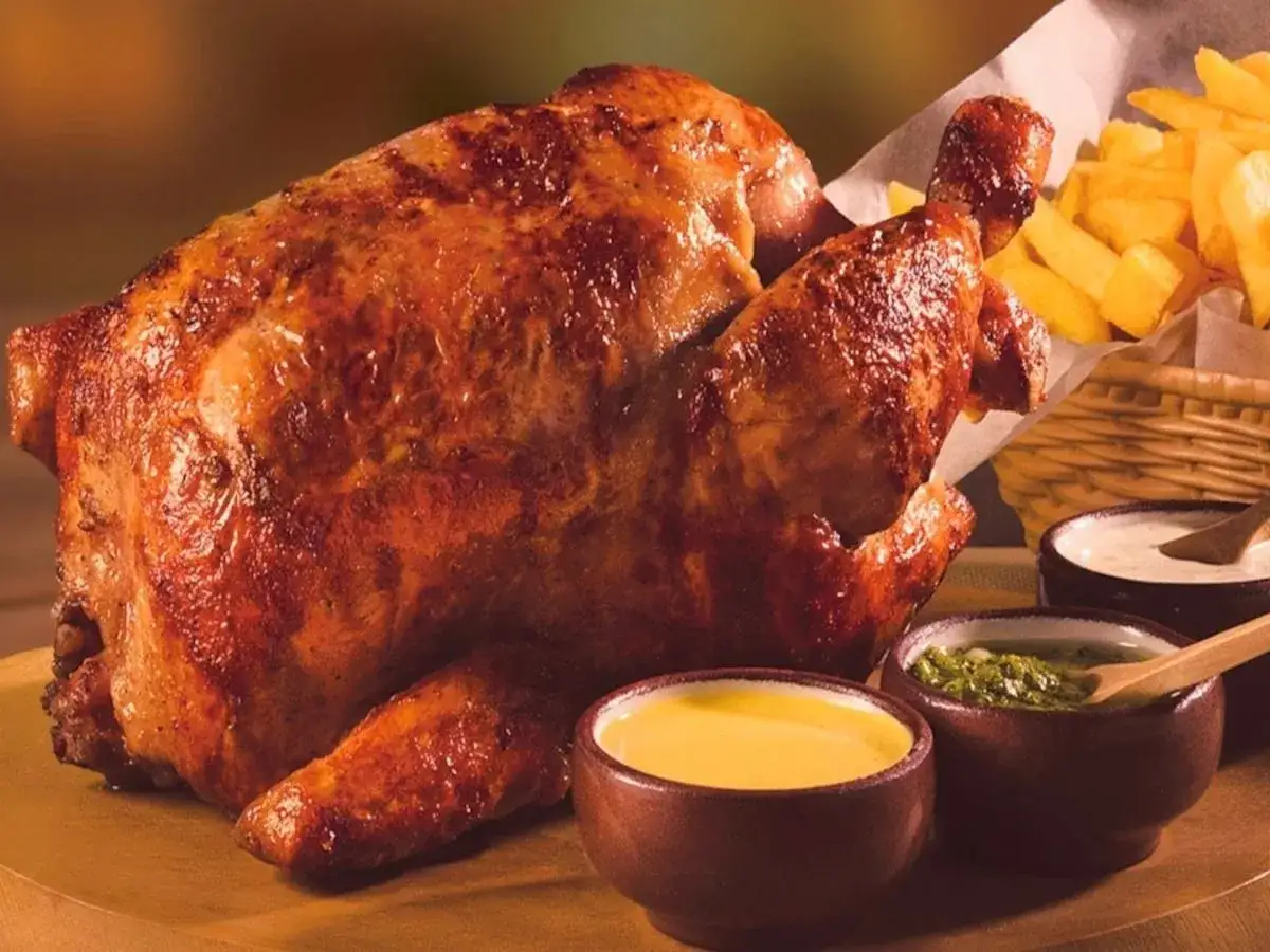 Pollo a la brasa dorado y jugoso, acompañado de papas fritas crujientes y salsas cremosas.