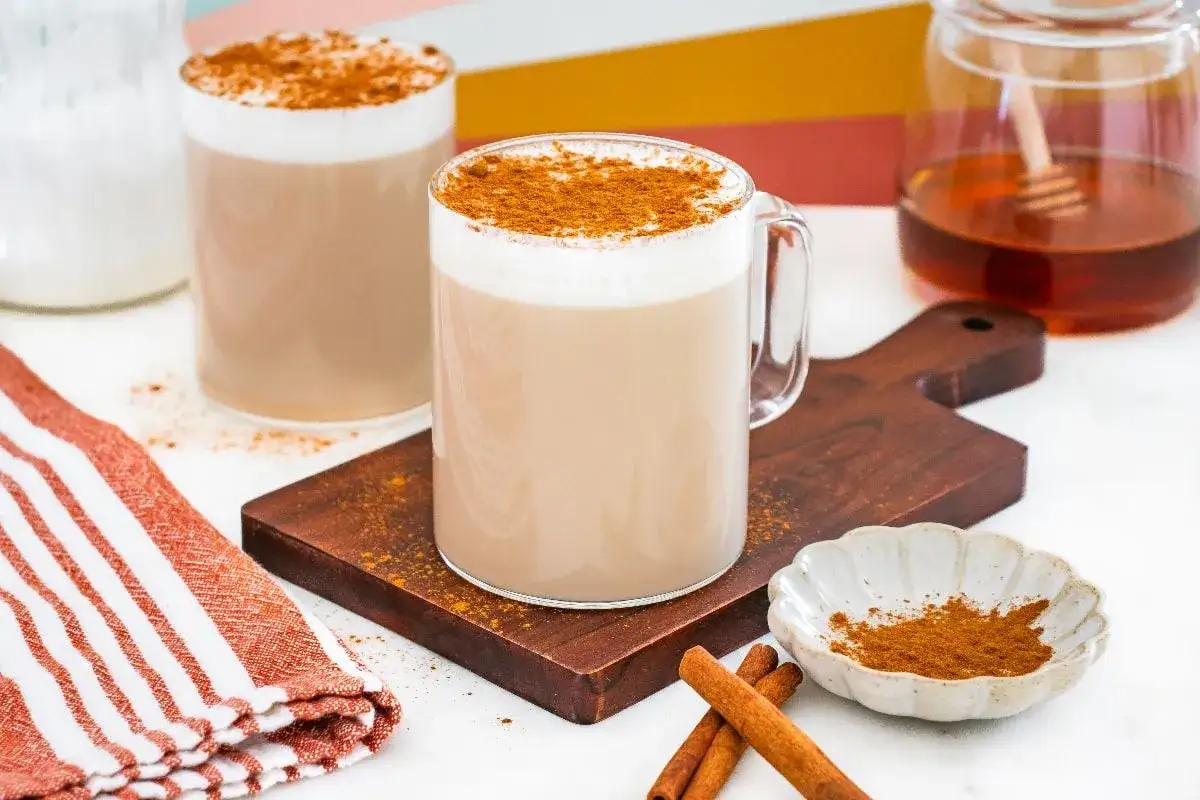 Dos tazas de leche con miel y canela espolvoreada, listas para disfrutar.