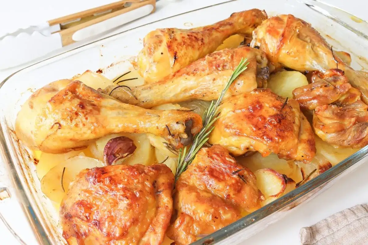 Pollo asado con patatas doradas, ajo y romero en una fuente de cristal. ¡Un plato casero irresistible!