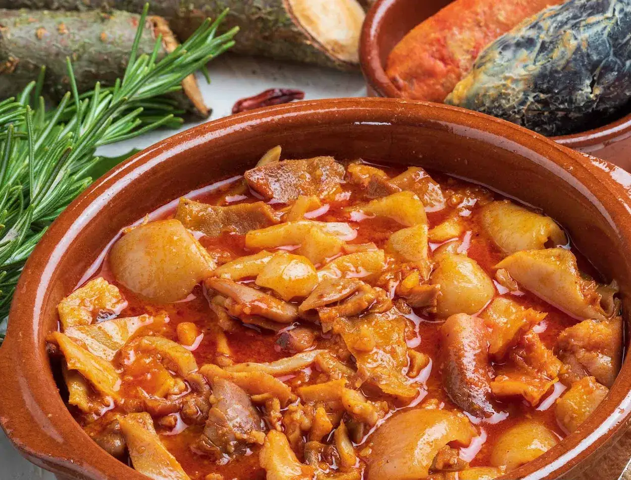 Un plato humeante de callos, como en las recetas de la abuela, con patatas y chorizo, decorado con romero.