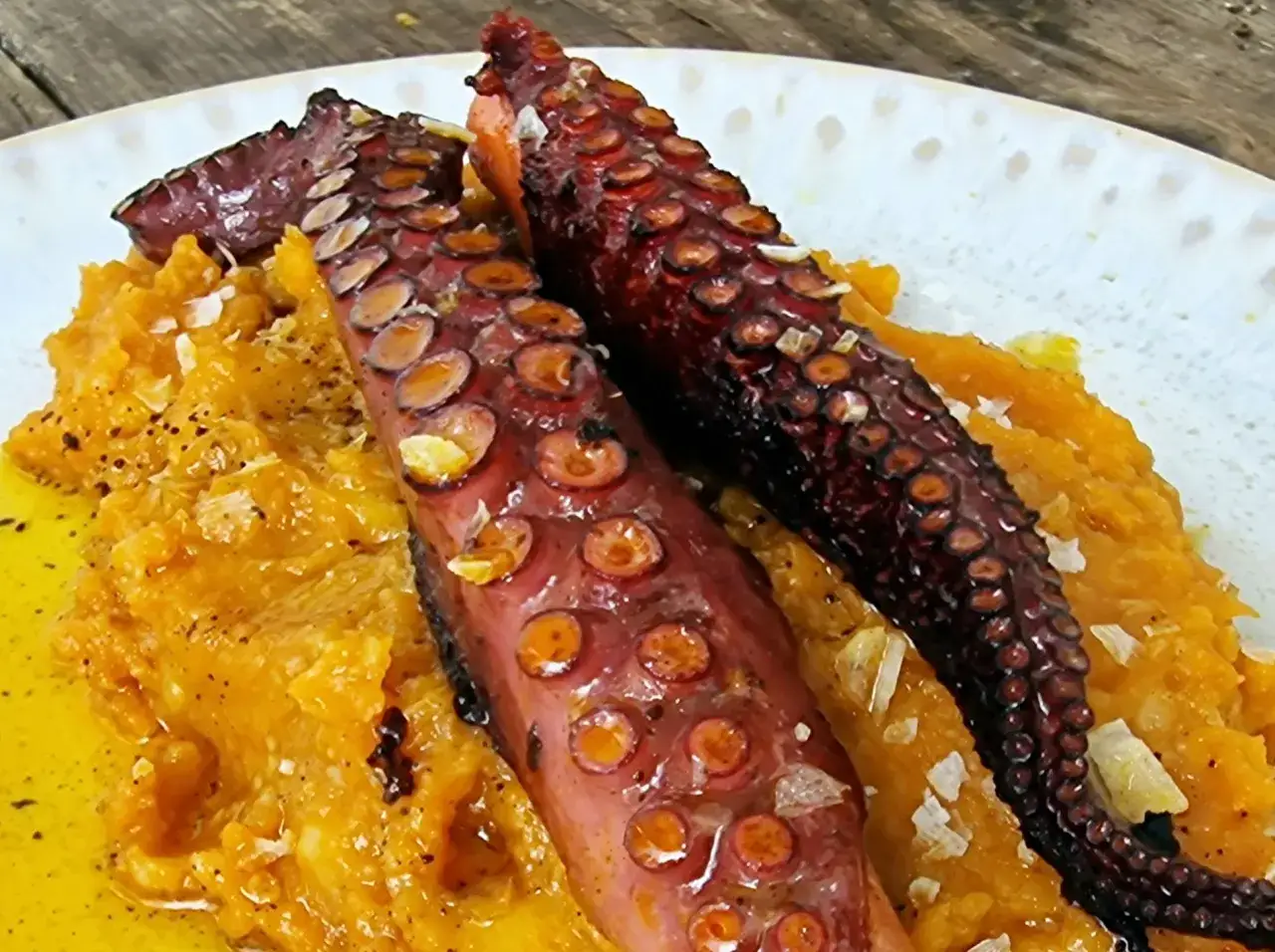 Delicioso pulpo con patatas cremosas, salpicado de escamas de sal y un chorrito de aceite de oliva.