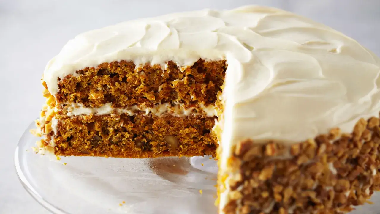 Tarta de zanahoria y nueces, con glaseado cremoso y trozos de nueces en los laterales. ¡Una delicia casera!