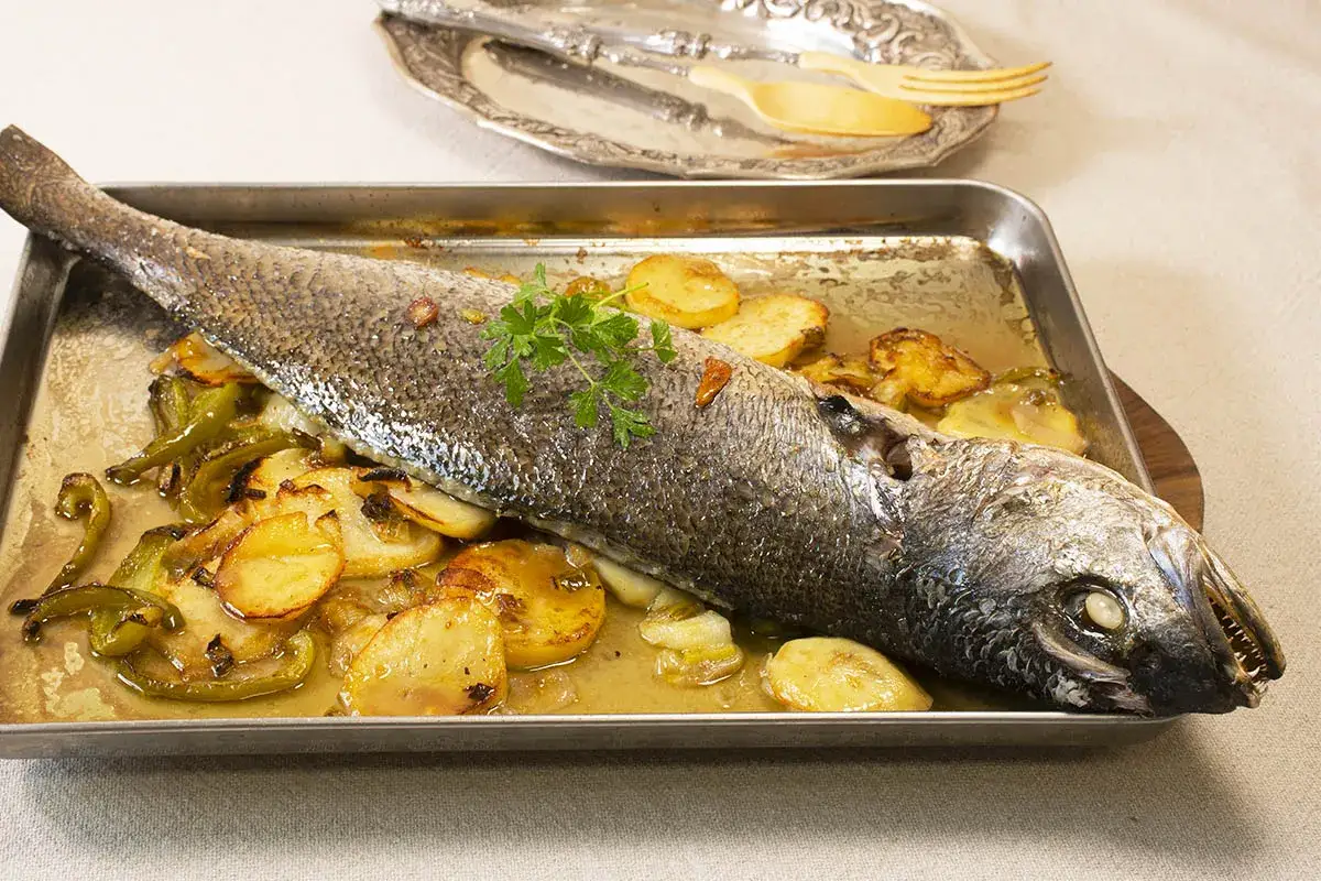 Corvina al horno con patatas y pimientos, lista para servir.