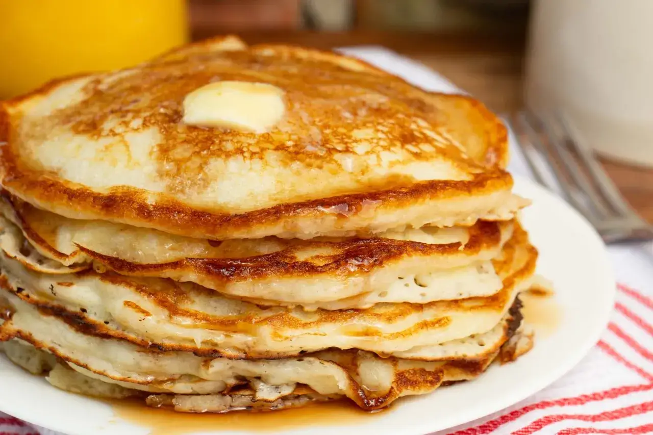 Una pila de tortitas doradas, cubiertas con una generosa porci&oacute;n de mantequilla derretida y sirope. &iexcl;Un desayuno perfecto de tortitas sin mantequilla a&ntilde;adida a la masa!