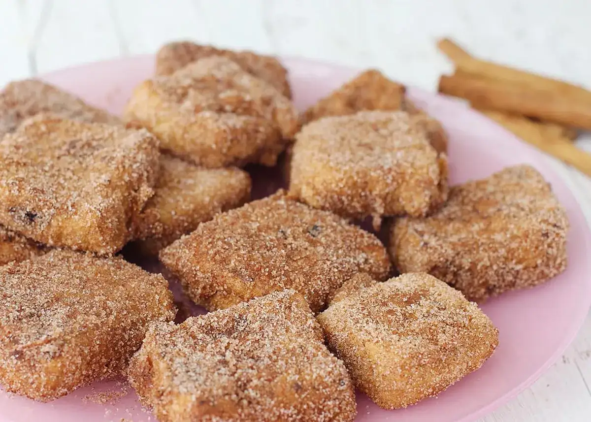Deliciosa leche frita Thermomix, rebozada en azúcar y canela, servida en un plato rosa.