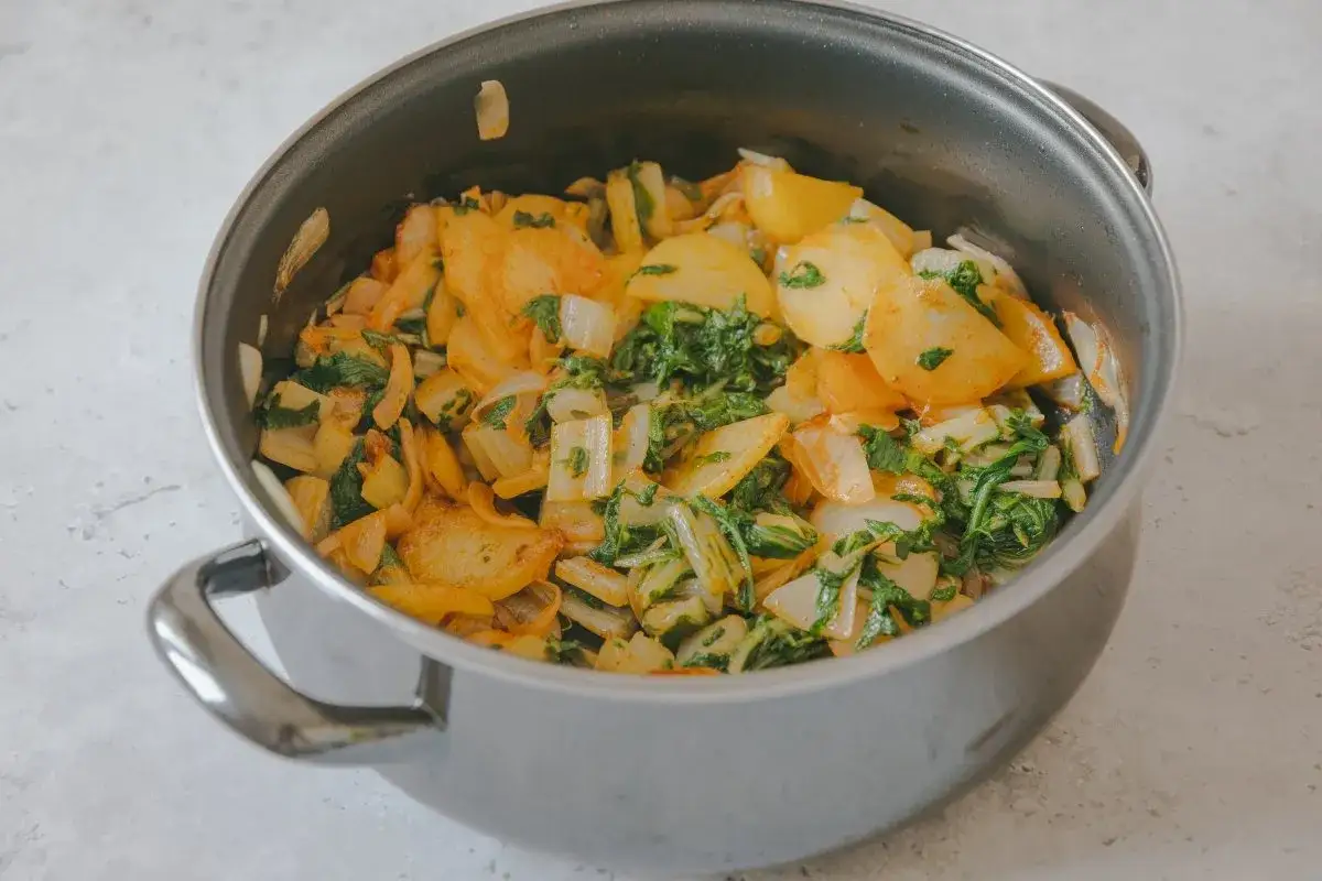 Un plato de acelgas a la extreme&ntilde;a reci&eacute;n hecho en una olla, con patatas y cebolla.