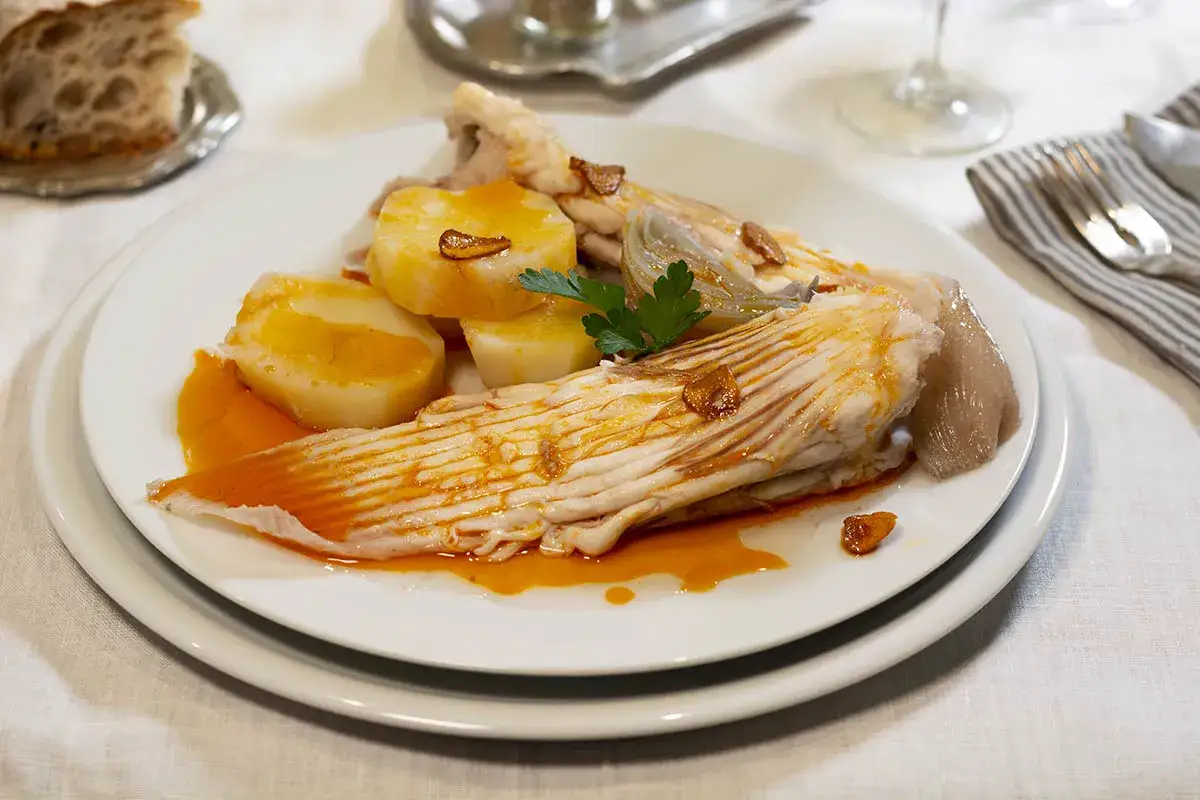 Raya a la gallega servida con patatas cocidas y un toque de ajo frito. Un plato tradicional gallego.