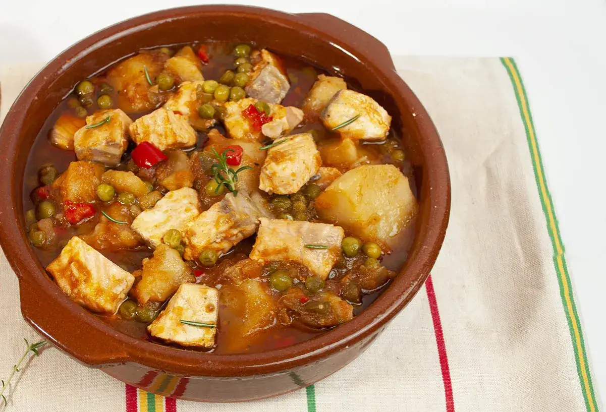 Un delicioso marmitako de salm&oacute;n con patatas, guisantes y pimientos rojos, servido en cazuela de barro.