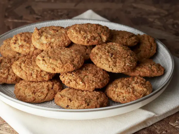 Montón de carajitos del profesor, galletas doradas y crujientes con avena y coco, apiladas en un plato gris.