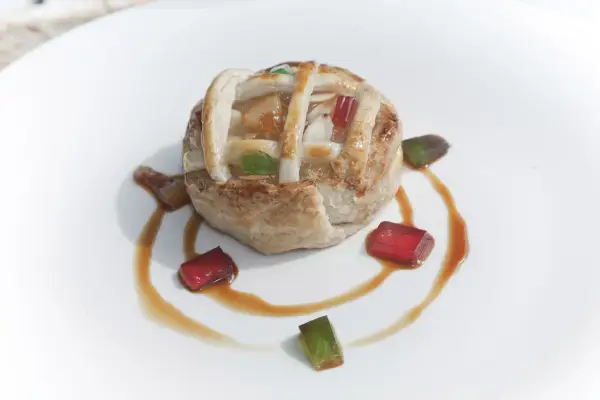 Deliciosa tarta de Mondoñedo, con su masa dorada y relleno de frutas, decorada con gominolas de colores y un sirope dulce.